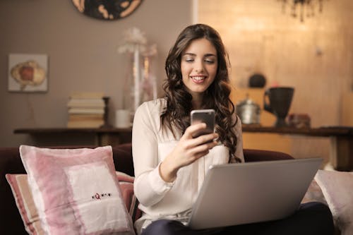 Personne utilisant son téléphone portable devant son ordinateur dans son salon