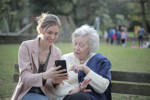 Jeune femme montrant quelque chose de drôle sur son téléphone à une personne âgée