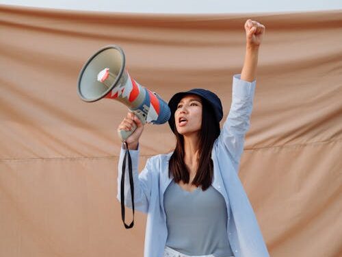 Femme le poing en l'air en train de parler au mégaphone