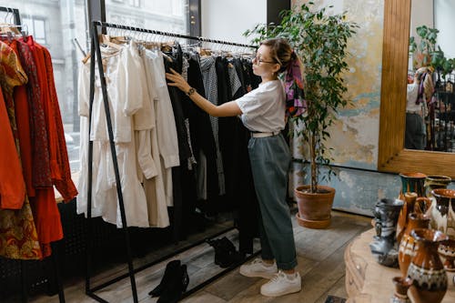 Jeune femme regardant les vêtements en vente dans un petit magasin de quartier