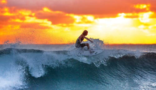 Surfer sur une vague au soleil couchant