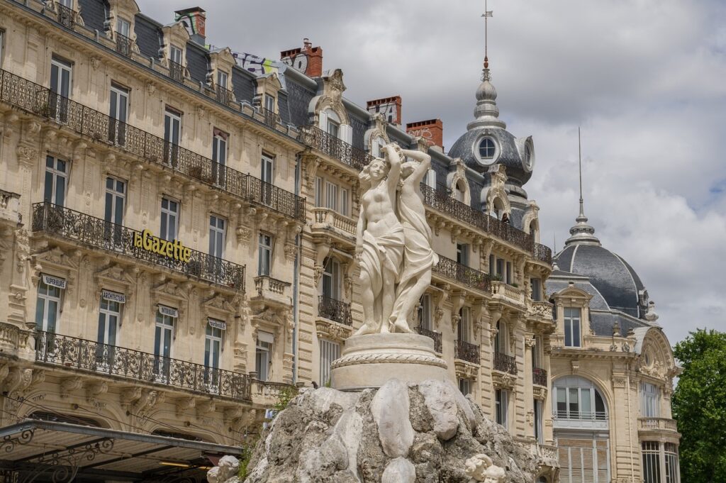 Statue des Trois Grâces sur la place de la Comédie à Montpellier, avec en arrière-plan les façades haussmanniennes et le bâtiment de la Gazette. Statue des Trois Grâces sur la place de la Comédie à Montpellier, avec en arrière-plan les façades haussmanniennes et le bâtiment de la Gazette.