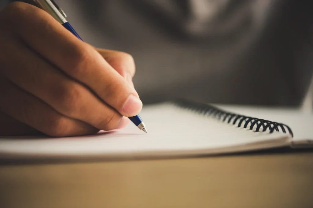 Personnes écrivant un texte sur un cahier pour être sur de ne pas perdre ses textes